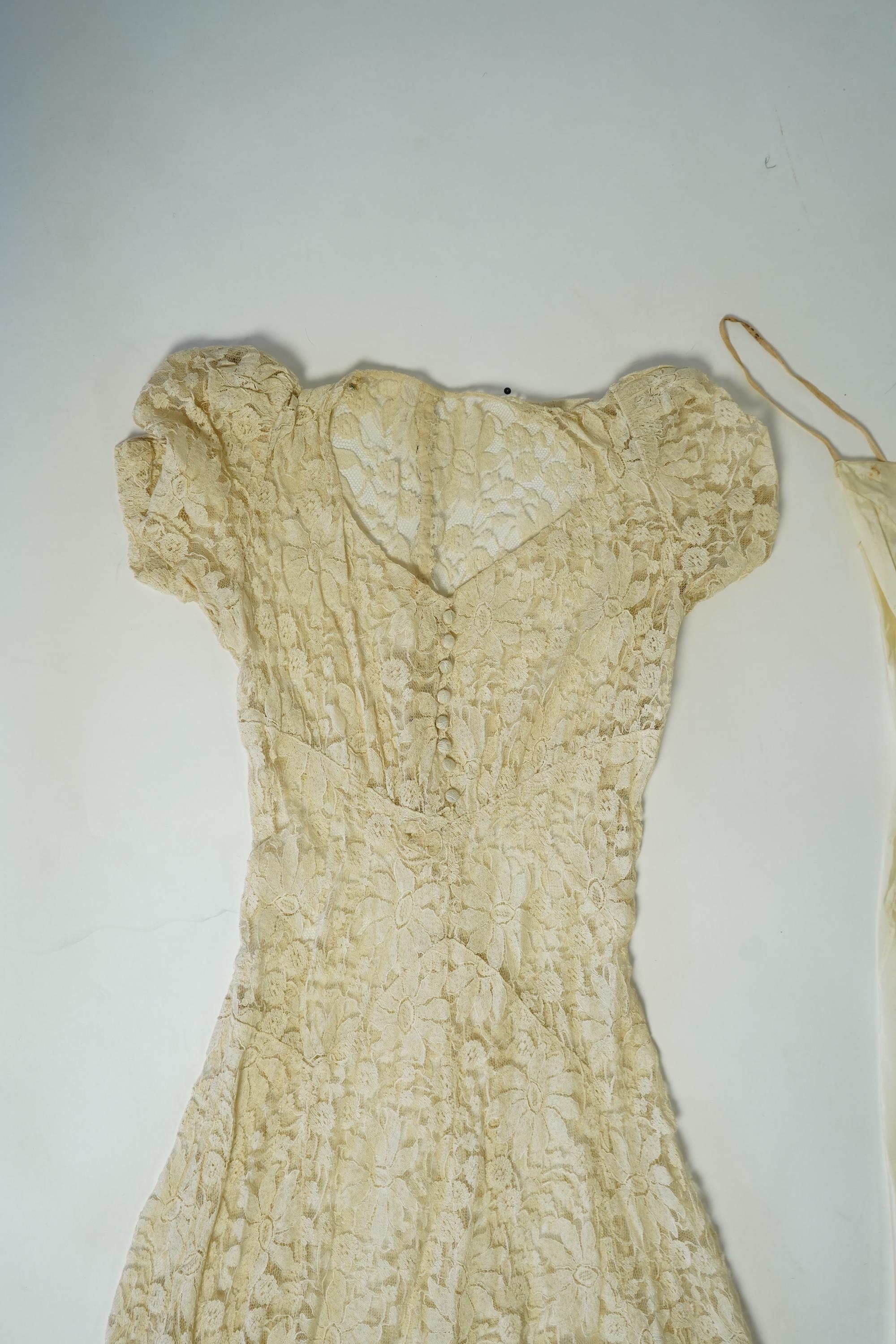 An early 1940's cream cotton lace and taffeta evening dress, with matching taffeta petticoat, possibly worn as a wedding dress., Dress 144cm long. Condition - minor repairs needed to lace in places and laundering to remo